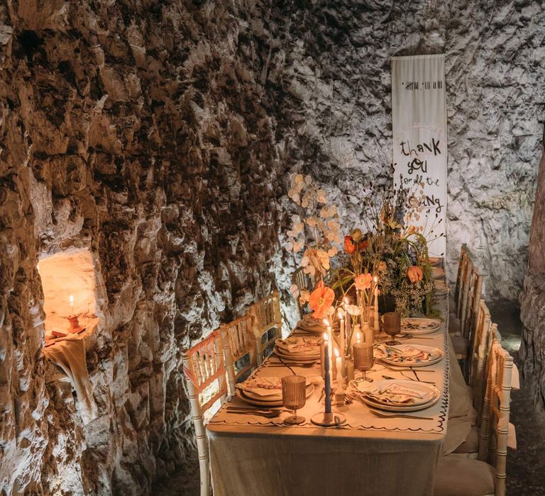 Eclectic abstract wedding tablescape at Margate Caves - neutral toned under table cloth, abstract design wedding tablecloth on top, twisted tapered candles in ceramic candlestick holders, gold cutlery, abstract wedding stationery, and dried flower centrepieces