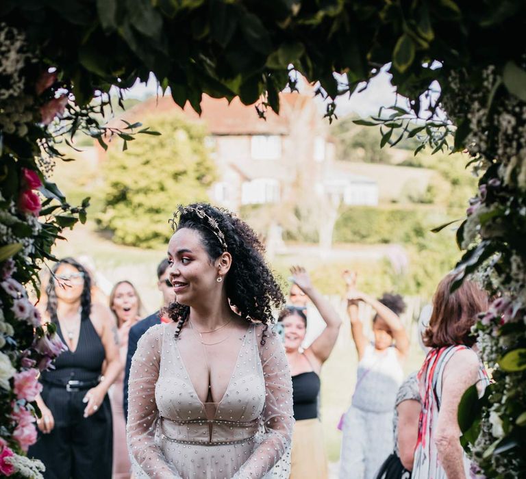 Bride in long sleeve v-neck sheer polka dot overlay sparkly wedding dress and gold celestial bridal headband holding rose and eucalyptus bridal bouquet 