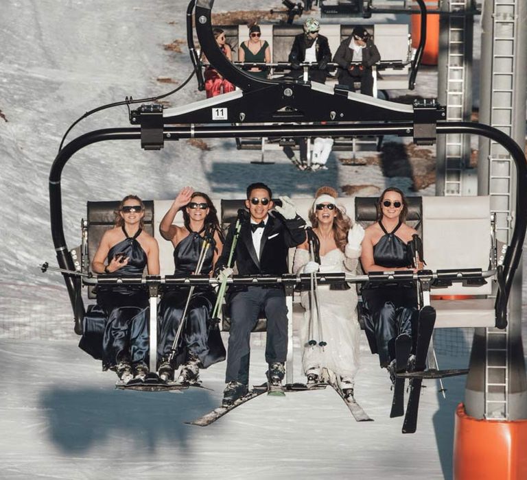 Wedding party going up on a ski lift at French destination ski wedding in The Alps