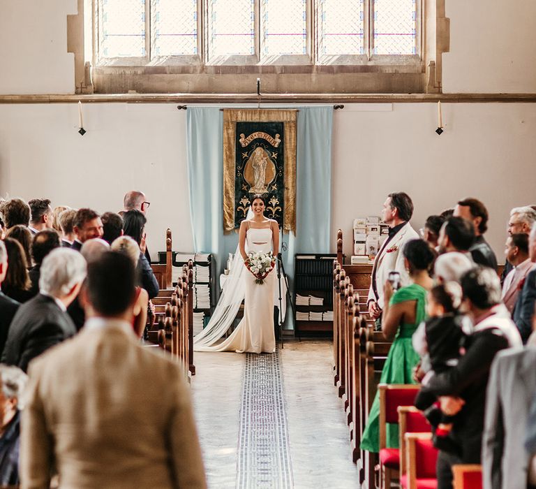 Bride walking down the aisle by herself to meet the groom at the end of the aisle 