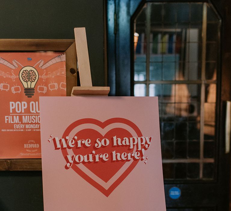 Pink and retro wedding welcome sign on wooden easel 