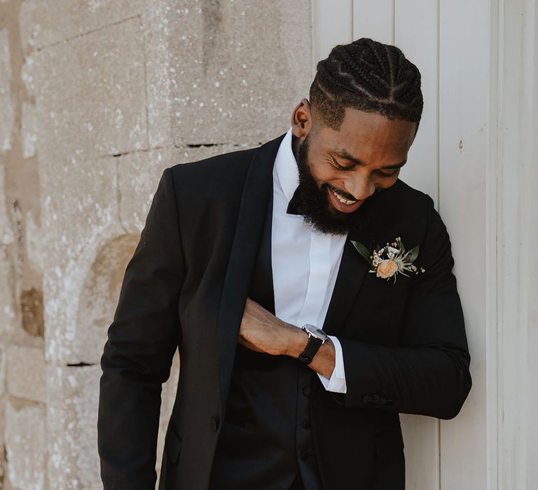 Black groom wearing a classic and traditional black tuxedo at historic wedding venue 