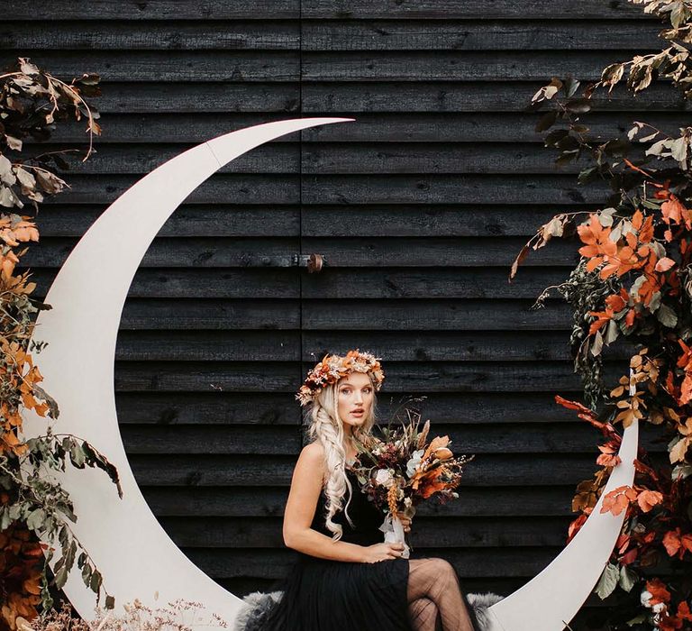 Bride in tulle black autumn wedding dress on crescent moon decoration at Halloween wedding 