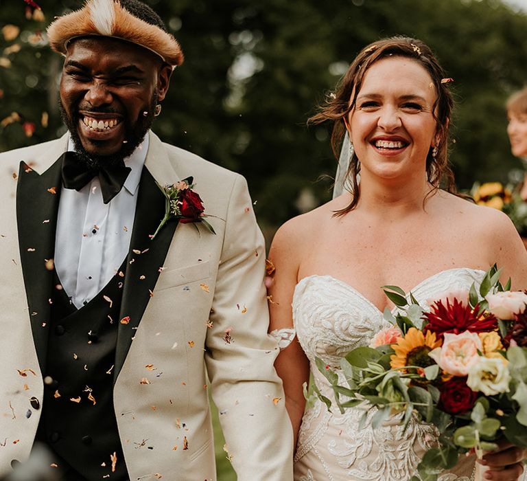 Confetti exit for the bride and groom outdoors after their church ceremony 