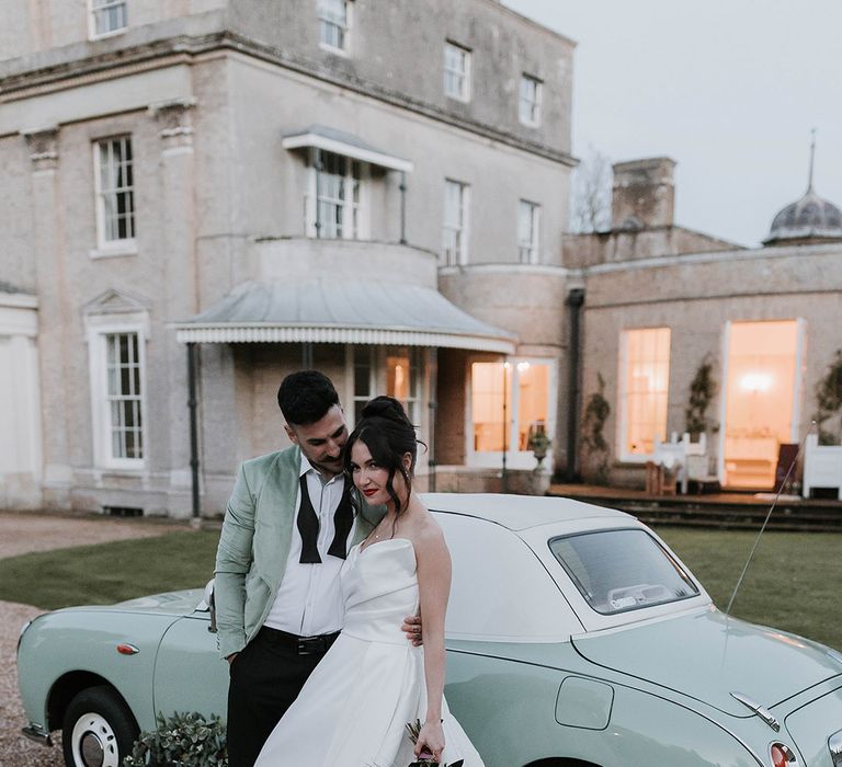 Vintage mint green wedding car with the bride in a princess wedding dress and groom in a green suit 