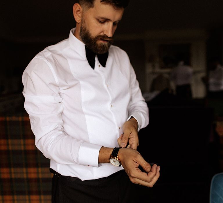 Groom in white shirt and black velvet bow tie getting ready for the wedding day 