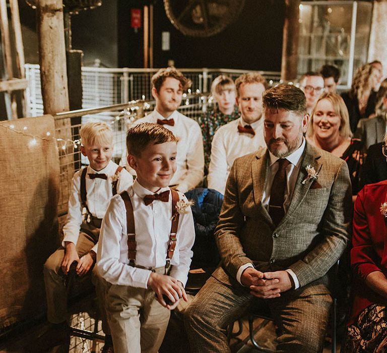 Kids at wedding wearing white shirts with brown bow ties and braces for retro industrial style wedding venue 