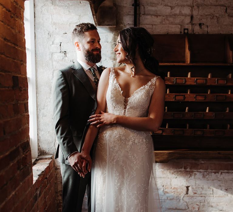 Bride in Madison James wedding dress with floral pattern smiling at the groom for couple portrait 