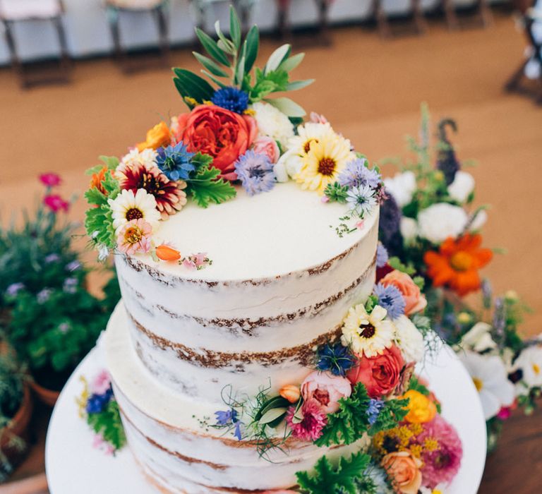 Semi-naked two tier wedding cake with bright and colourful wedding flower decorations 