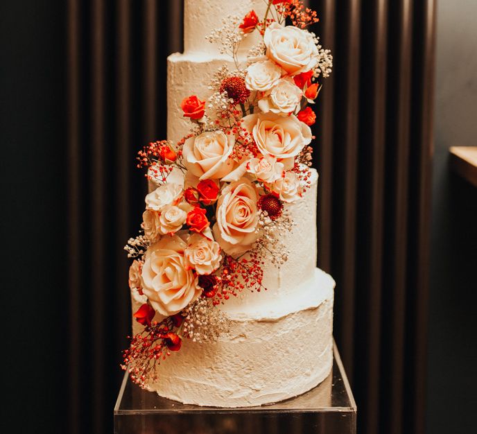 Four tier wedding cake with red spray-painted gypsophila installation