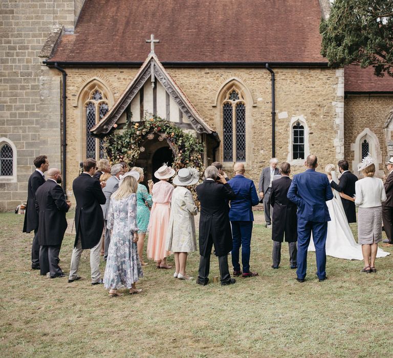 Micro wedding with guests standing outside the church 