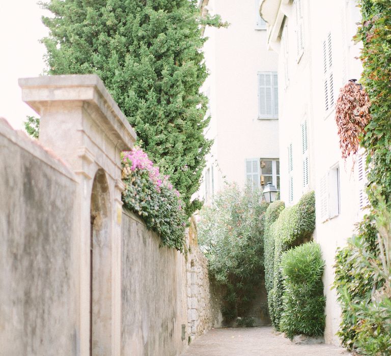 A French alleyway with old stonework and a greenery lined buildings