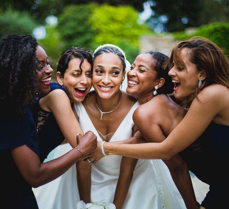 Bridesmaids all huddling around the bride to give her a big hug at her Chateau wedding in South of France