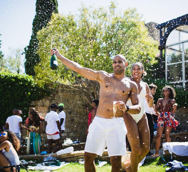 The groom spraying champagne at the next day pool party