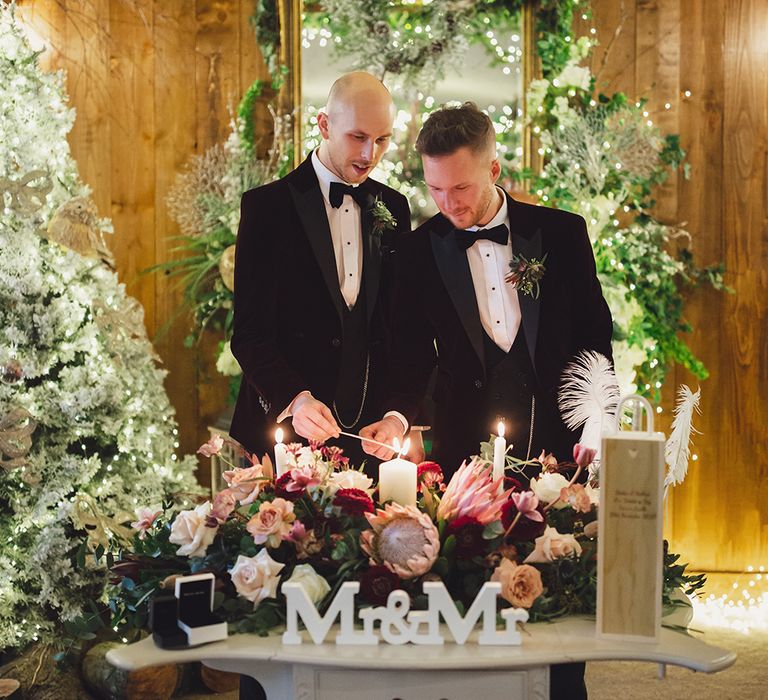 A gay couple cut their wedding cake in front of a Mr and Mr sign.