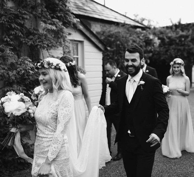 Bride in Grace Loves Lace wedding dress and single tier cathedral length veil walks with groom in black Hugo Boss suit at Drenagh Estate Wedding