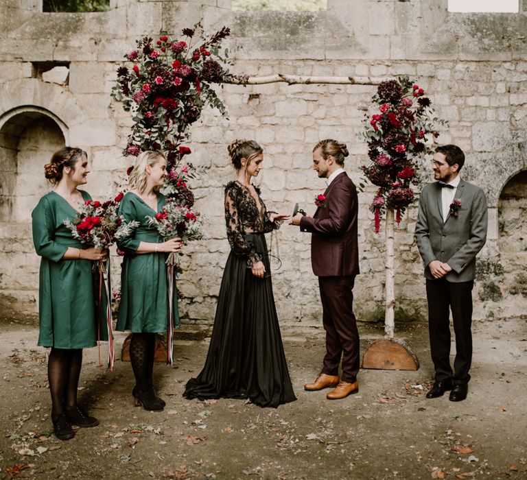 Gothic style wedding ceremony with bridesmaid in dark green dresses and bride in a black wedding dress