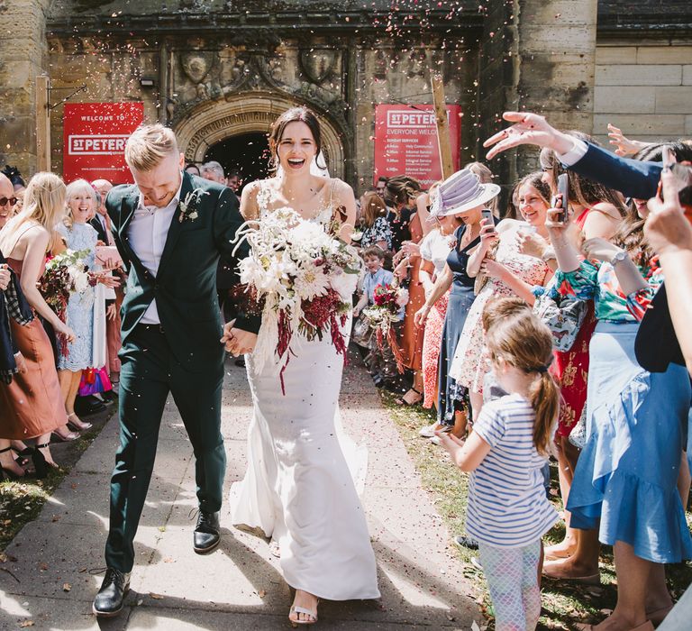 Bride & groom leaving church with confetti being thrown around them