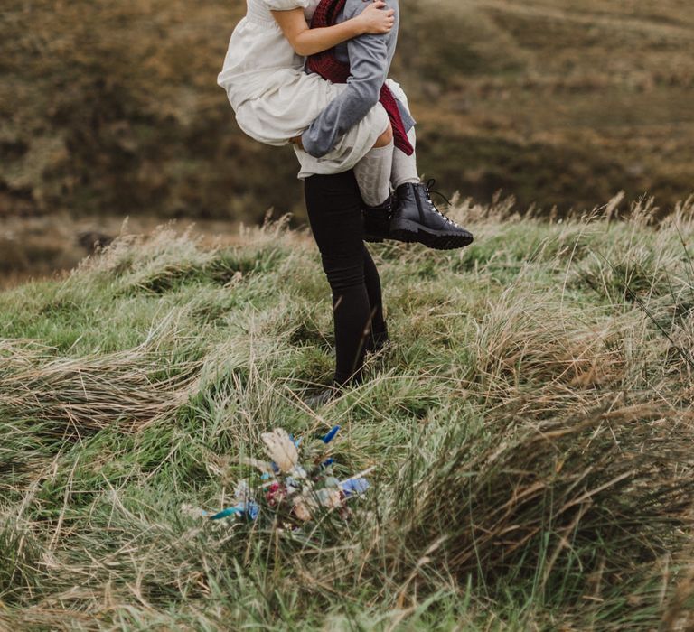 Two brides at the Peak District, one being lifted up in the other's arms