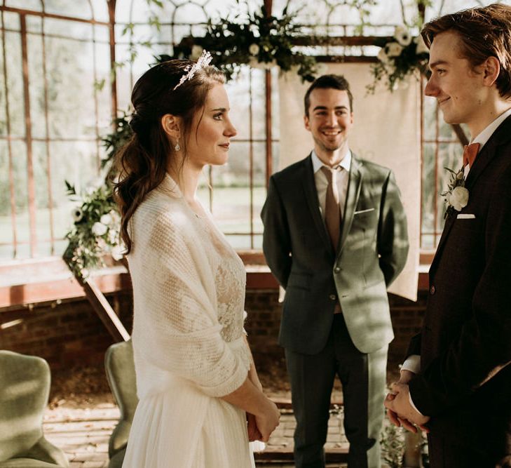 Bride in a wrap and crown exchanging vows at a nature wedding 