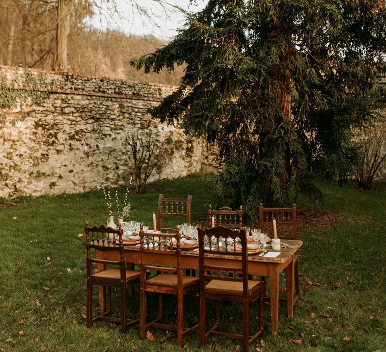 Outdoor nature wedding reception decor with wooden table and chairs