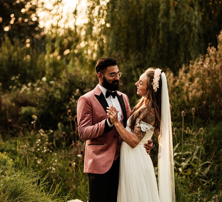 Bride & groom stand outdoors and embrace during their garden party wedding