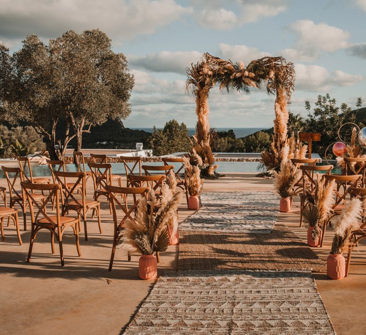 Outdoor ceremony decor with woollen rugs, dried flowers arrangements and floral arch 