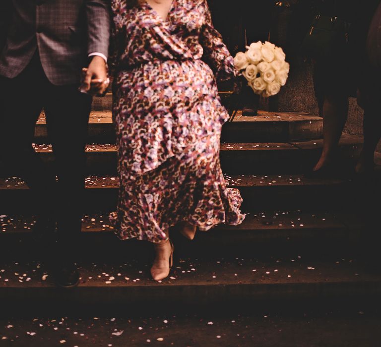 Bride & groom walk down steps with confetti at their feet after it has been thrown