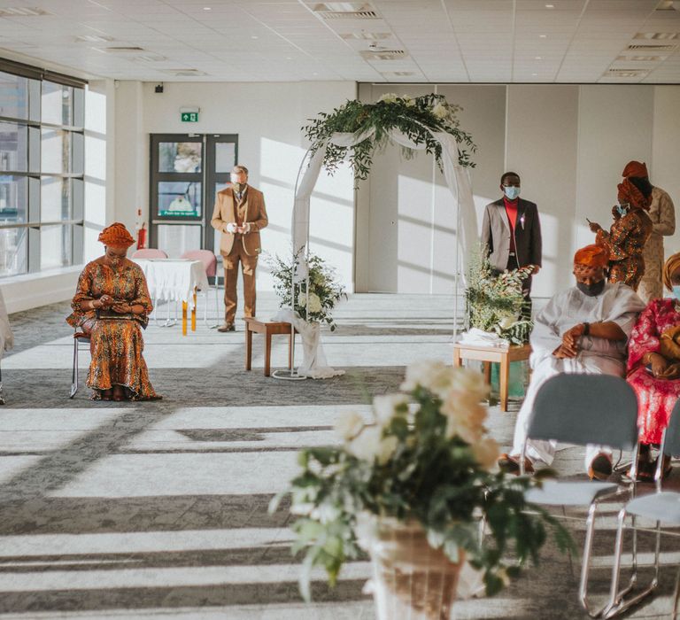 Guests in colourful outfits sit socially distanced waiting for the bride at Bridge Community Church wedding