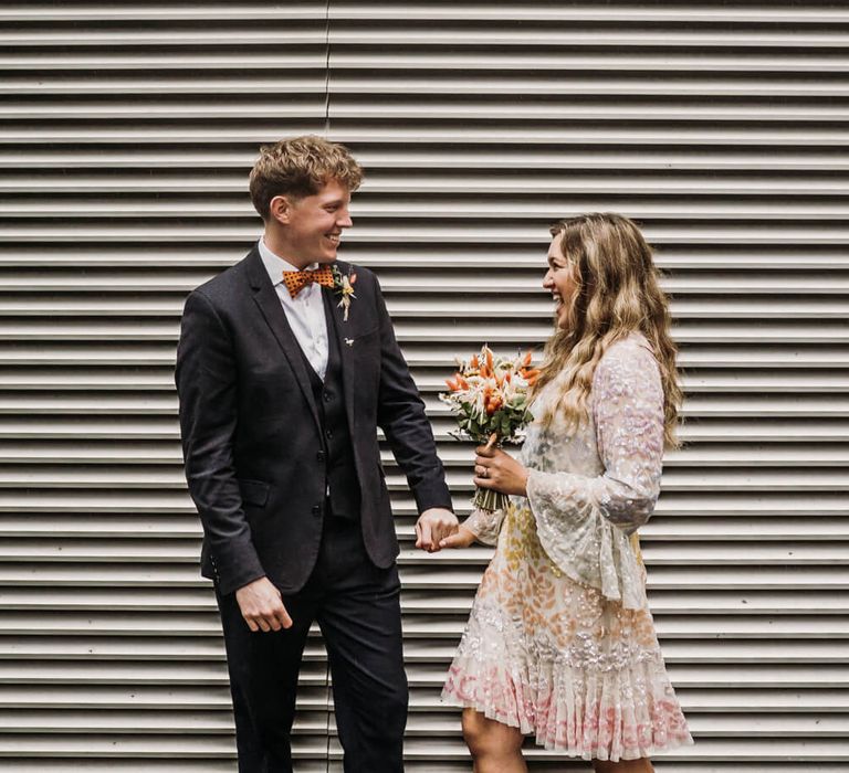 Bride and groom photography, groom wears orange polka dot bow tie and bride wears multi-colored pastel wedding dress