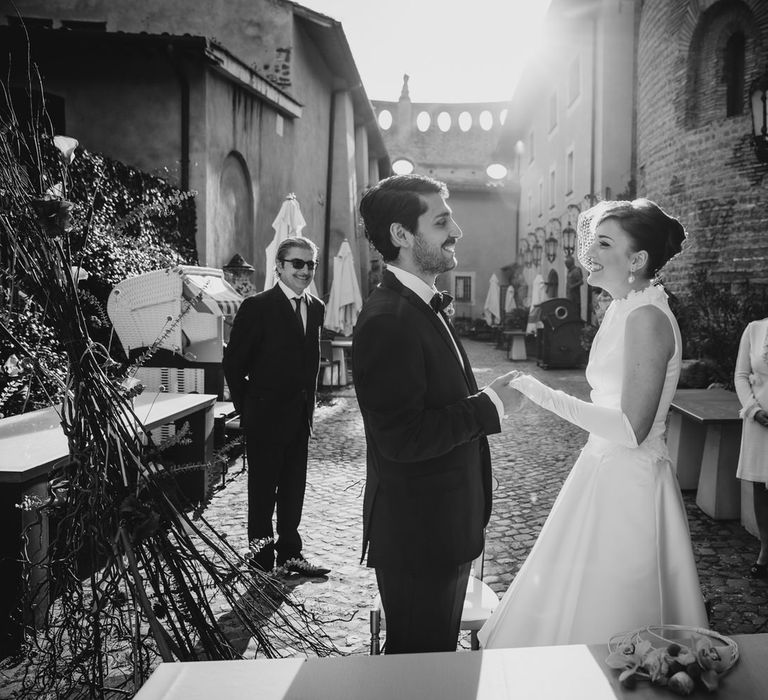 The bride and groom at the altar, their two guests behind them smiling and looking on