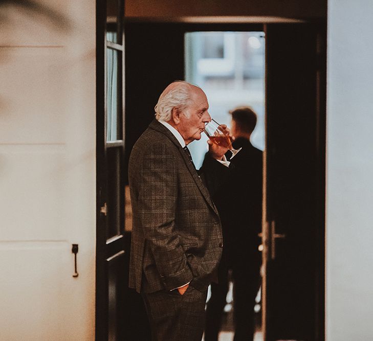 The Bride's grandad drinking beer in a brown checked suit 