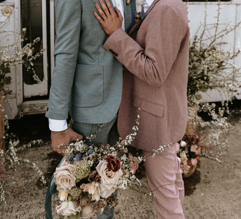 Groom leans into groom whilst stood outdoors at The Fire Pit Camp