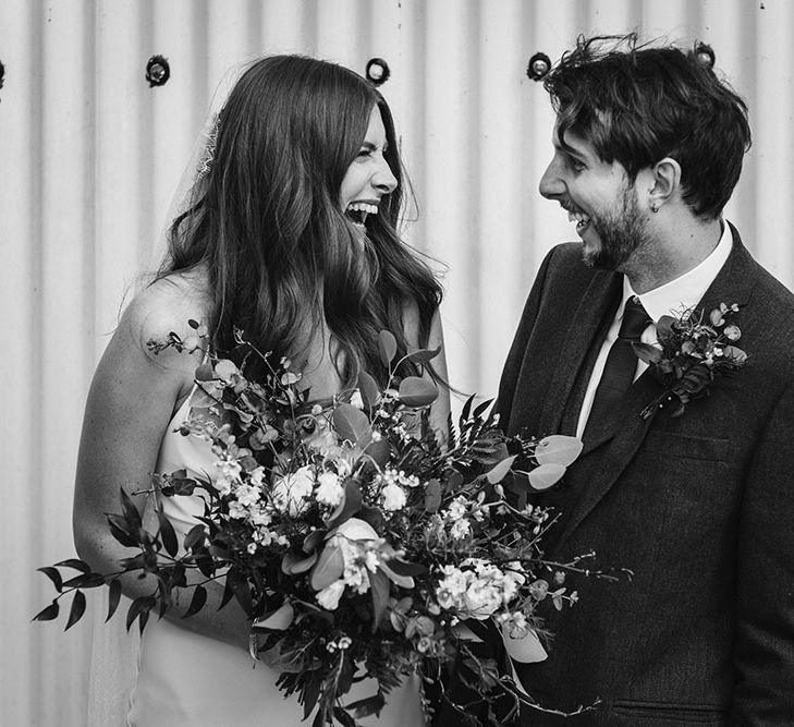 Black and white portrait of the bride and groom laughing 