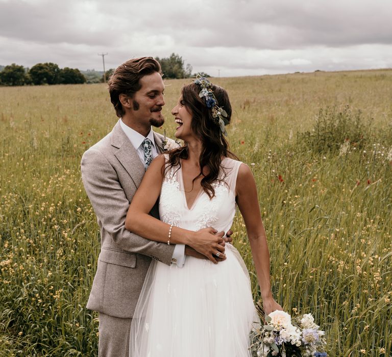 Groom kisses bride as he wraps his arm around her waist