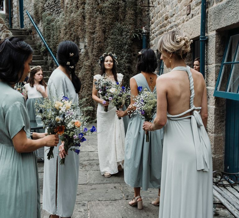 Bride reveals herself in wedding gown to bridesmaids outdoors before wedding ceremony