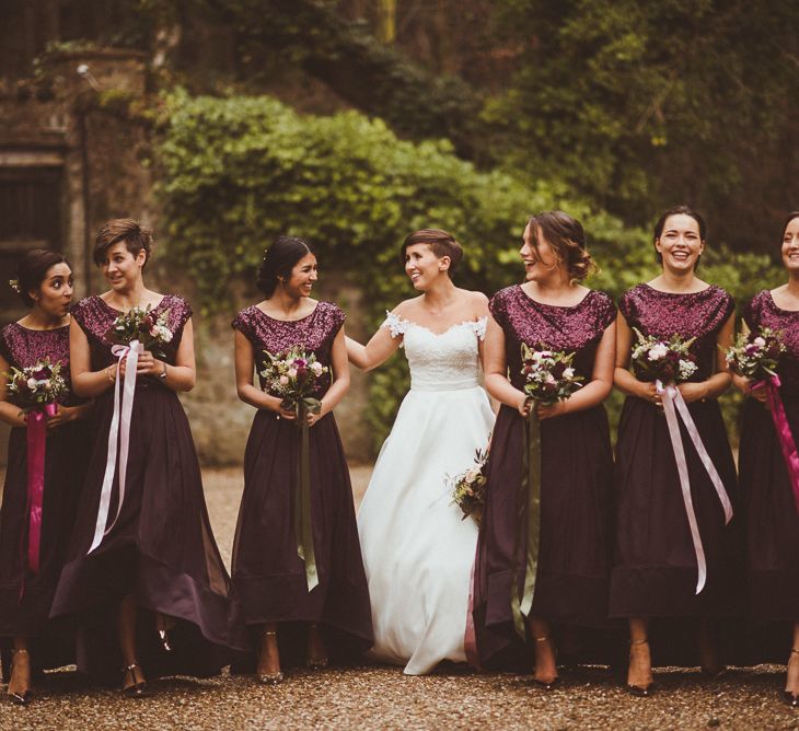 Bridal party portrait with bridesmaids in burgundy high low skirts and sparkly tops for winter, Christmas wedding