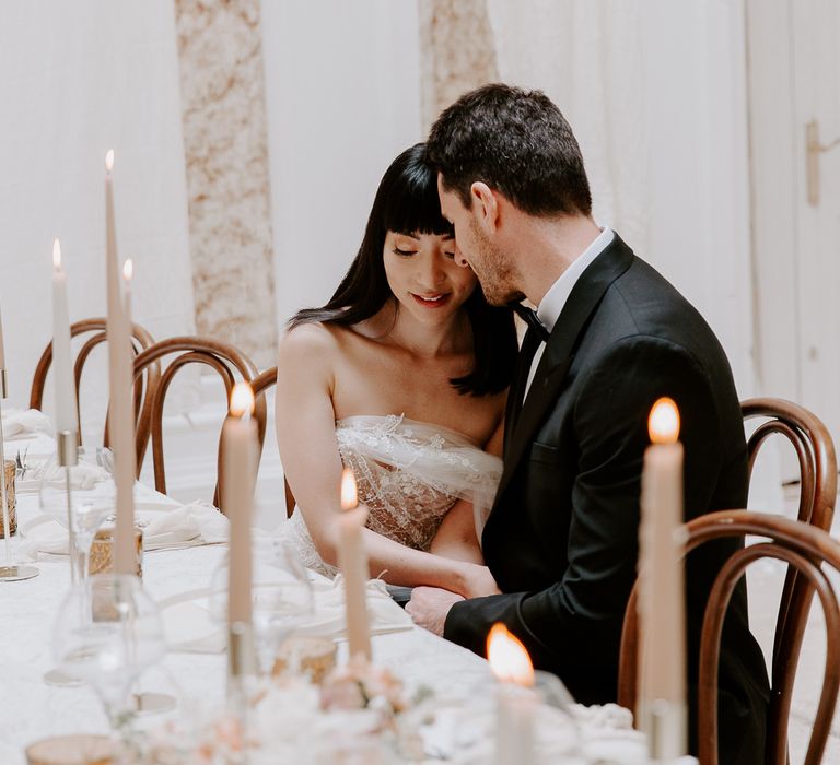 Intimate bride and groom portrait at the minimalist wedding reception table decorated with taper candles 