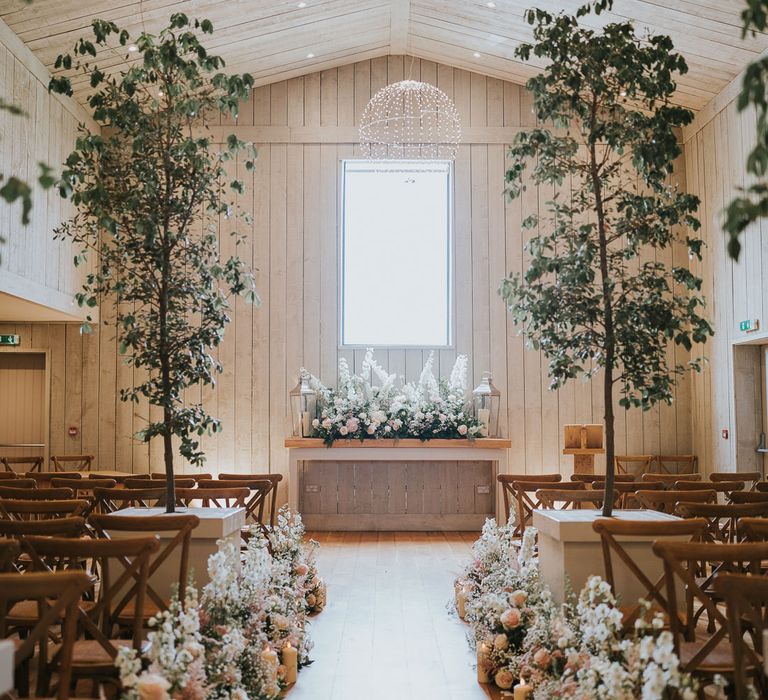 Wedding ceremony barn at Primrose Hill Farm with wooden chairs, white and pink florals and trees for summer wedding