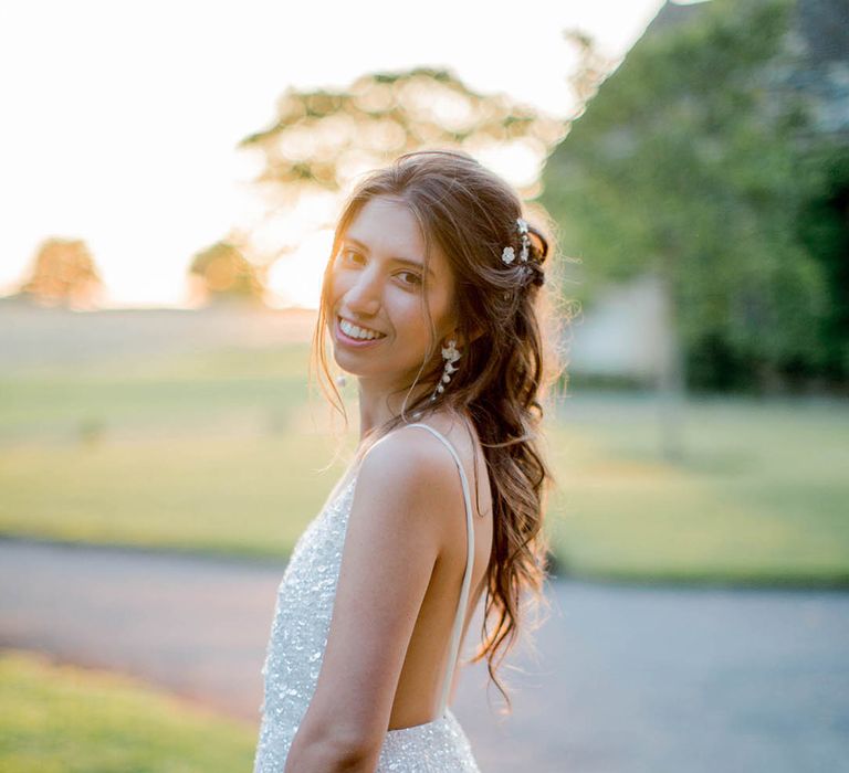 Bride looks back across her shoulder on her wedding day whilst stood outdoors