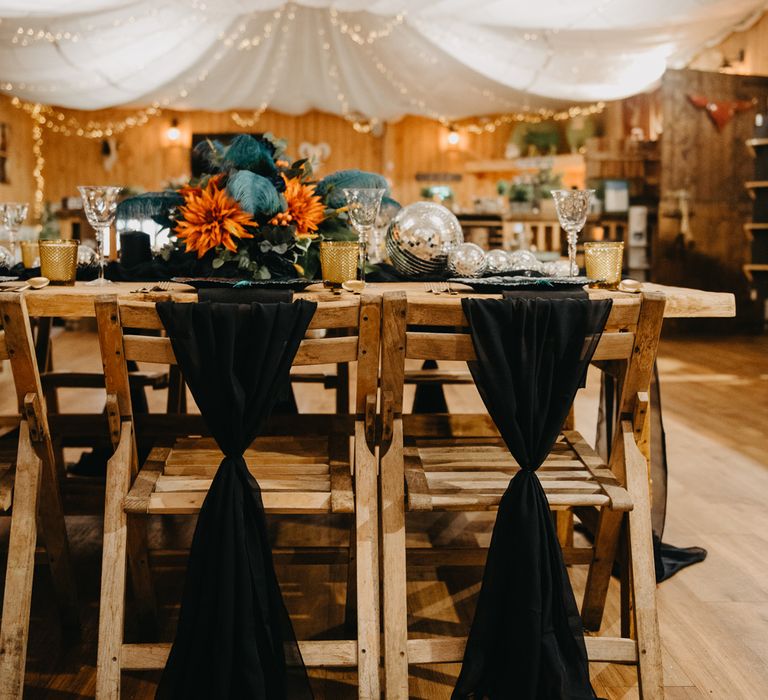 Rustic wedding reception with wooden tables and chairs, blue and orange flowers and fairy lights