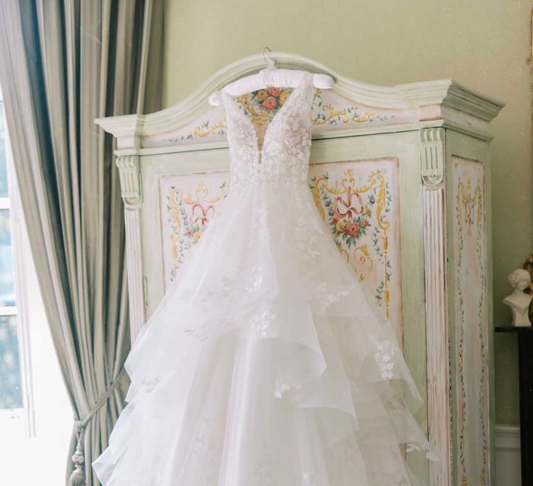 Layered tulle and lace Martina Liana wedding dress hanging on a wardrobe 