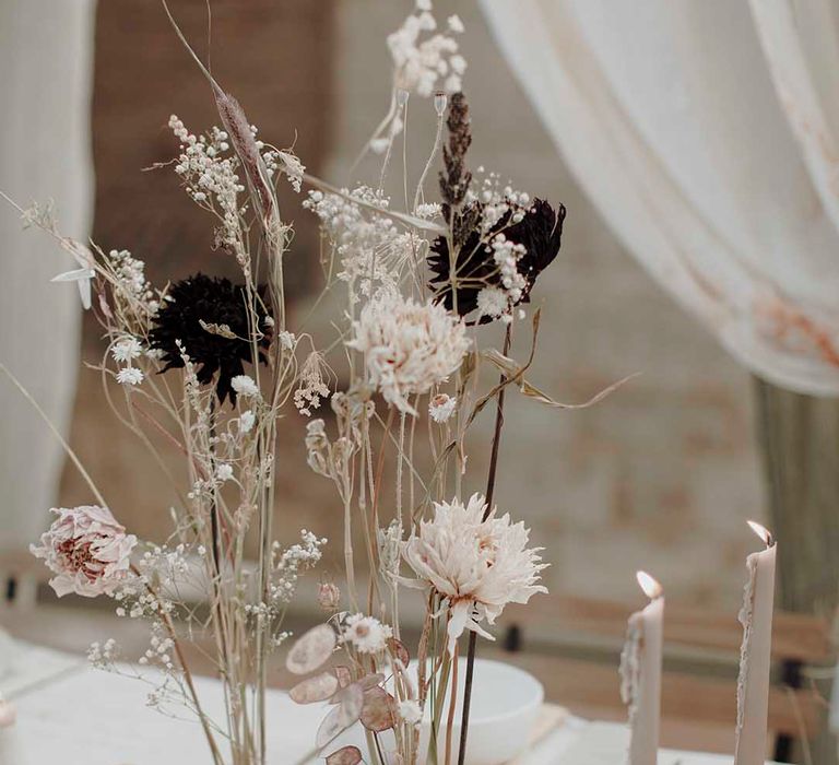 minimalist wedding table decor with taper candles and long dried flower stems in finger bowls 