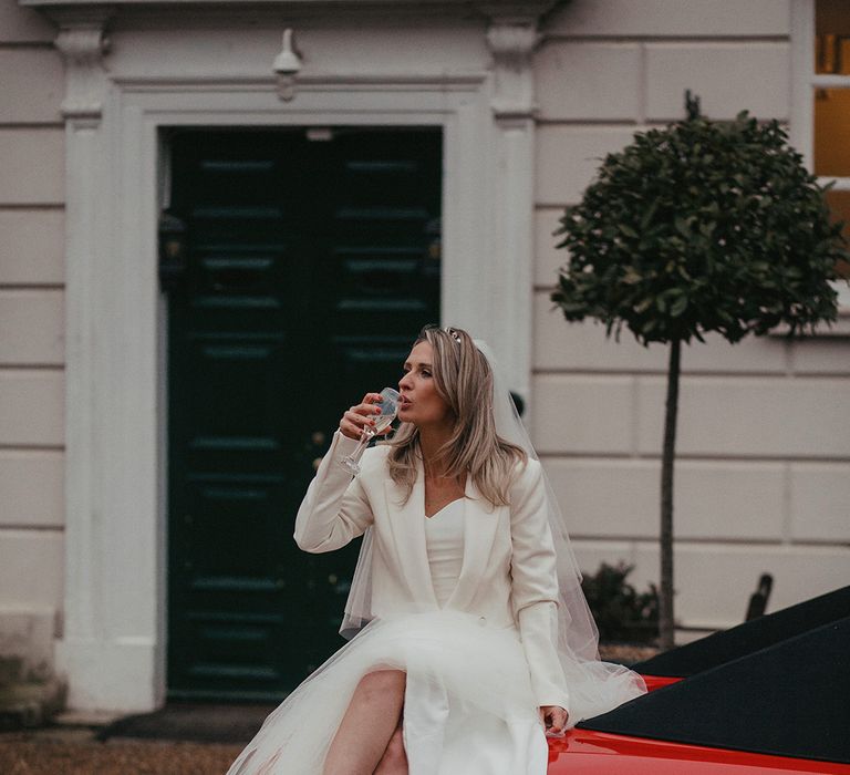 Bride sips champagne on red Ferrari and wears Zara jacket with yellow Manolo Blahniks 