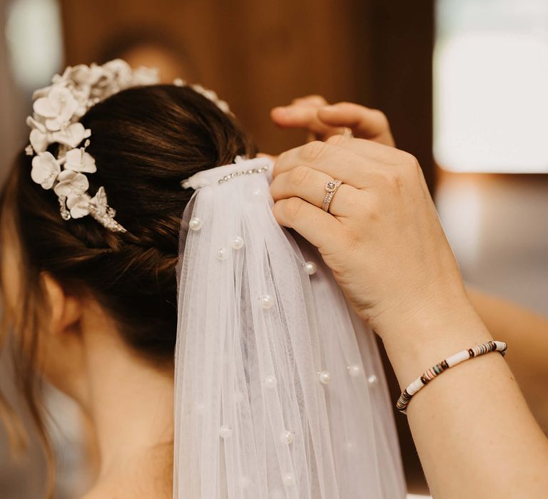 Bride has pearl veil added to a low up-do on her wedding day in sleek black hair