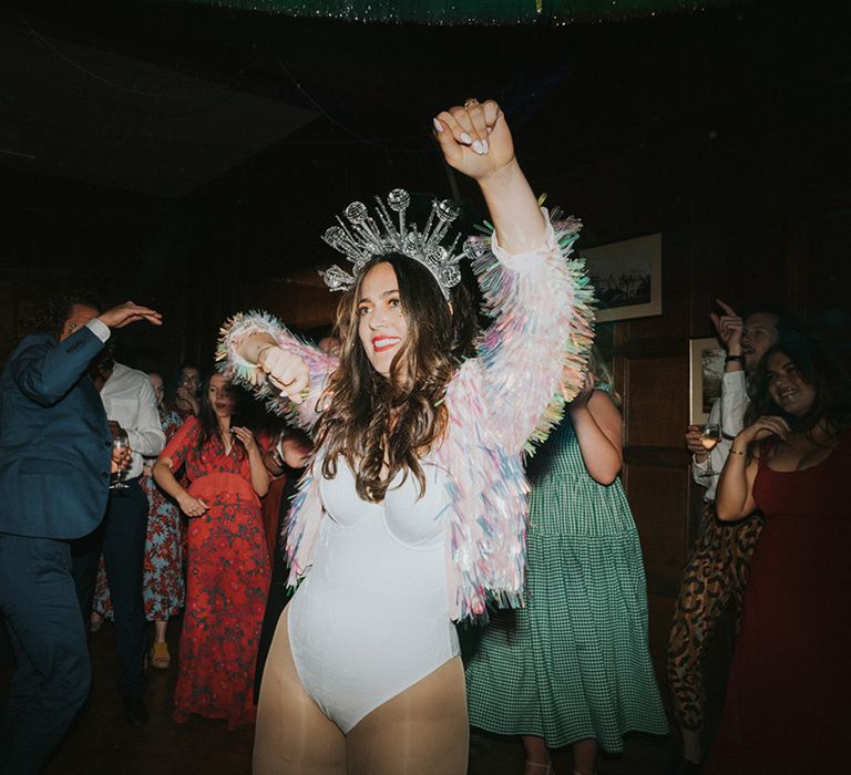 Bride in holographic tassel jacket, white bodysuit and disco ball crown parties hard at the wedding reception