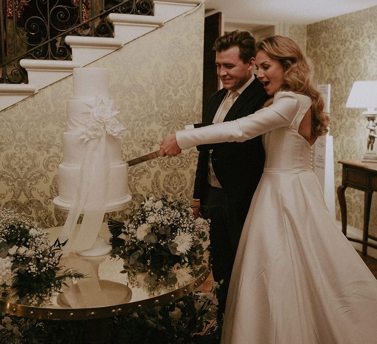 Bride and groom cutting large white semi-naked wedding cake at Hedsor House wedding