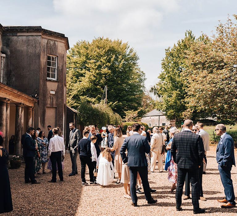 Wedding guests socialise outside Pennard House wedding venue