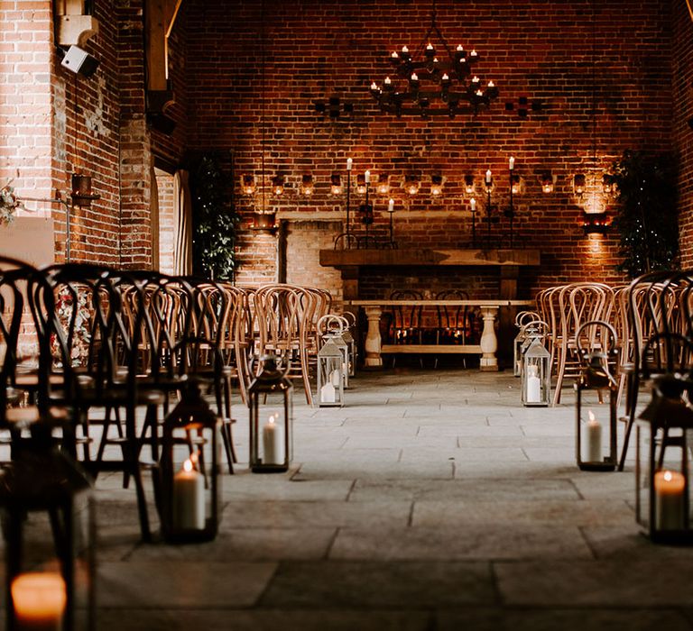 Candle chandelier and candles lining the aisle at cosy and rustic venue