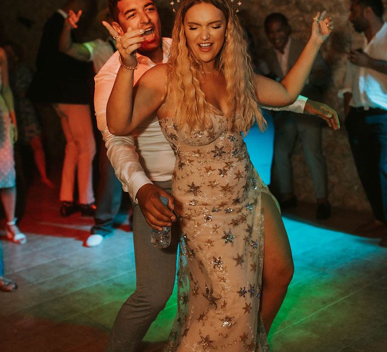 Bride in a celestial wedding dress and crown dancing at her evening reception 